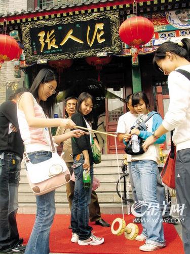几个天津姑娘在“泥人张”前玩传统游戏“空竹”