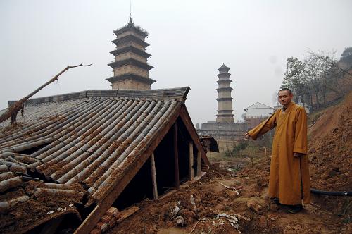 陕西长安华严寺的僧人介绍滑坡对寺庙造成的破坏(11月21日摄)。 位于陕西西安市长安区少陵原畔的佛教华严宗祖庭——华严寺内仅存的两座古塔面临着山体滑坡造成的巨大威胁。 华严寺内现存的两座古塔于2006年被纳入第六批全国重点文物保护单位。在2011年5月、6月和9月的数次集中降雨中,华严寺周边多处发生山体滑坡,其中建于唐代的杜顺塔的塔基已在滑坡中部分裸露,距离古塔一米左右的地面上裂开了长达数米的裂缝,妙觉塔旁的斋房的地基也遭到极大破坏,寺院内的其他房屋也在滑坡中遭到不同程度的损坏。 由于近期西安仍不时出现降雨天气,已经遭到较大破坏的华严寺古塔目前面临着极大的滑坡威胁。 新华社记者 李一博 摄
