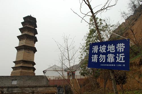 陕西长安华严寺内的妙觉塔旁挂起了“滑坡地带 请勿靠近”的警示牌(11月21日摄)。 位于陕西西安市长安区少陵原畔的佛教华严宗祖庭——华严寺内仅存的两座古塔面临着山体滑坡造成的巨大威胁。 华严寺内现存的两座古塔于2006年被纳入第六批全国重点文物保护单位。在2011年5月、6月和9月的数次集中降雨中,华严寺周边多处发生山体滑坡,其中建于唐代的杜顺塔的塔基已在滑坡中部分裸露,距离古塔一米左右的地面上裂开了长达数米的裂缝,妙觉塔旁的斋房的地基也遭到极大破坏,寺院内的其他房屋也在滑坡中遭到不同程度的损坏。 由于近期西安仍不时出现降雨天气,已经遭到较大破坏的华严寺古塔目前面临着极大的滑坡威胁。 新华社记者 李一博 摄