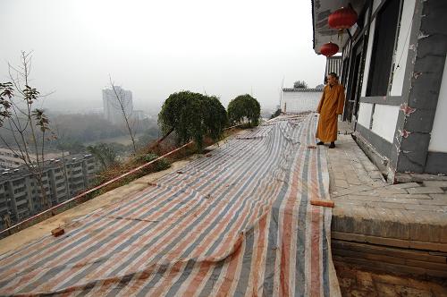 僧人在陕西长安华严寺内查看滑坡危险区的情况(11月21日摄)。 位于陕西西安市长安区少陵原畔的佛教华严宗祖庭——华严寺内仅存的两座古塔面临着山体滑坡造成的巨大威胁。 华严寺内现存的两座古塔于2006年被纳入第六批全国重点文物保护单位。在2011年5月、6月和9月的数次集中降雨中,华严寺周边多处发生山体滑坡,其中建于唐代的杜顺塔的塔基已在滑坡中部分裸露,距离古塔一米左右的地面上裂开了长达数米的裂缝,妙觉塔旁的斋房的地基也遭到极大破坏,寺院内的其他房屋也在滑坡中遭到不同程度的损坏。 由于近期西安仍不时出现降雨天气,已经遭到较大破坏的华严寺古塔目前面临着极大的滑坡威胁。 新华社记者 李一博 摄