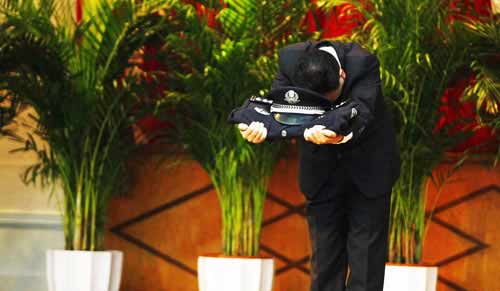 原重庆市局刑警总队二支队副支队长郑某手托警服警帽向全场鞠躬